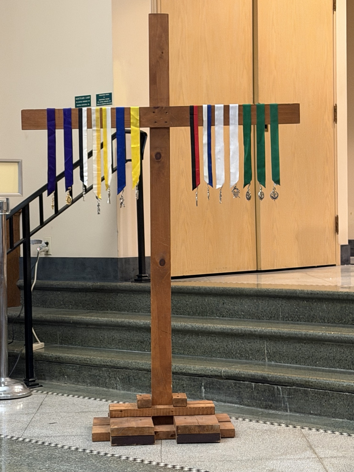 Council officers’ jewels displayed on a wooden cross for the July 7, 2026 installation.