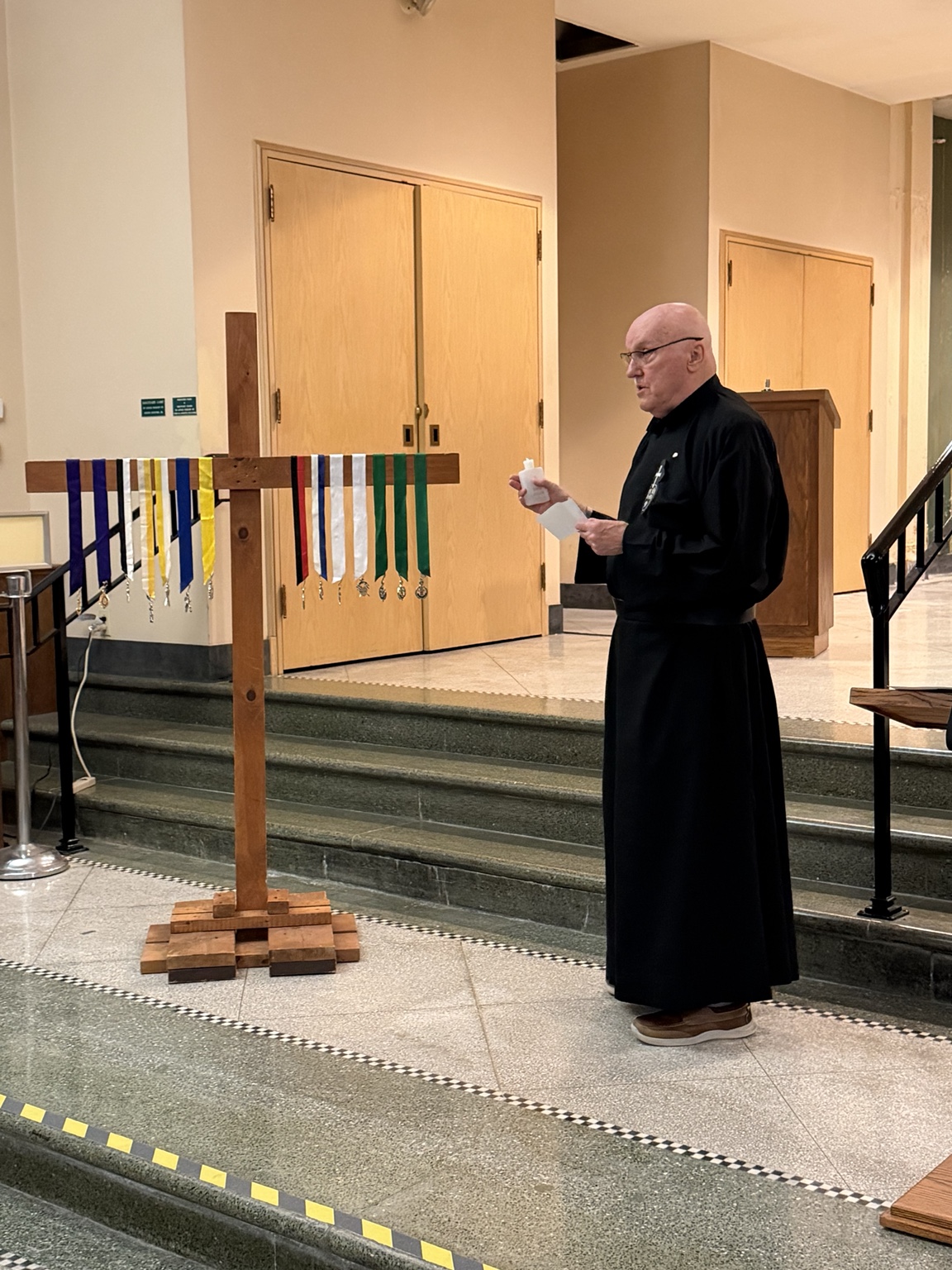 The priest blesses the medals of office displayed on the cross during the July 7, 2026 installation.